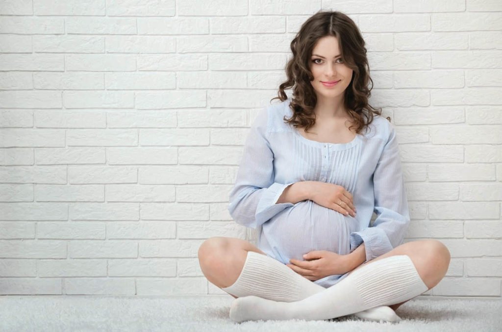 Беременная девушка сидит на полу