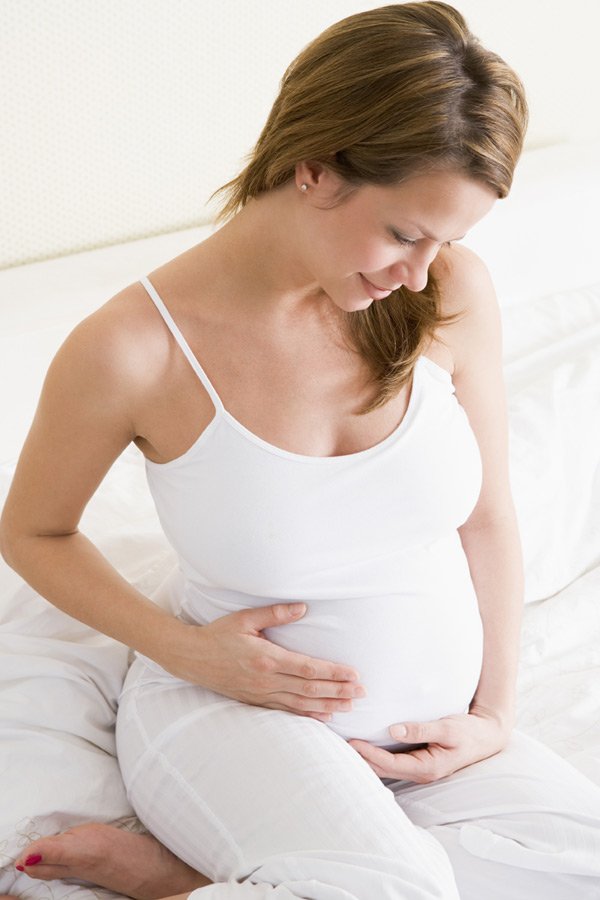 Беременная женщина гладит свой живот