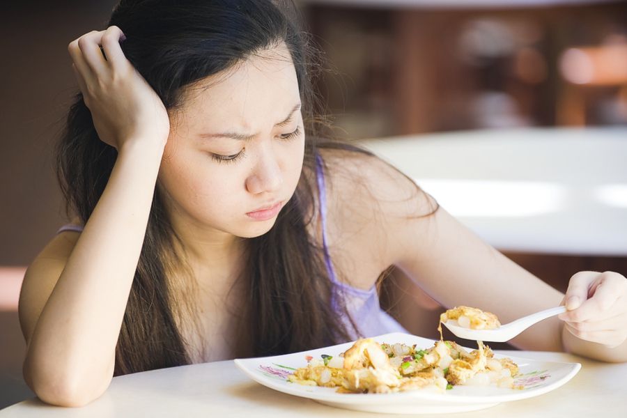 Девушка смотрит на салат и страдает от отсутствия аппетита